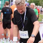 Członek drużyny XEMI Team podczas biegu charytatywnego Plum Ekiden przy stoisku z wodą