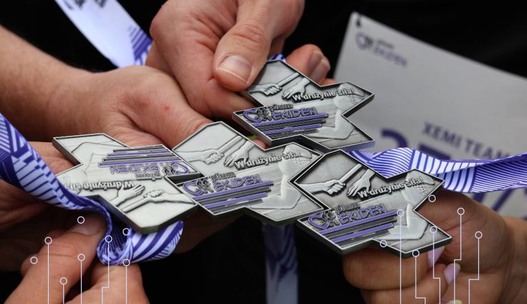 Medale sztafety charytatywnej Plum Ekiden trzymane przez uczestników z zespołu XEMI TEAM i XEMISIE, symbolizujące współpracę, zaangażowanie i wsparcie inicjatyw społecznych.