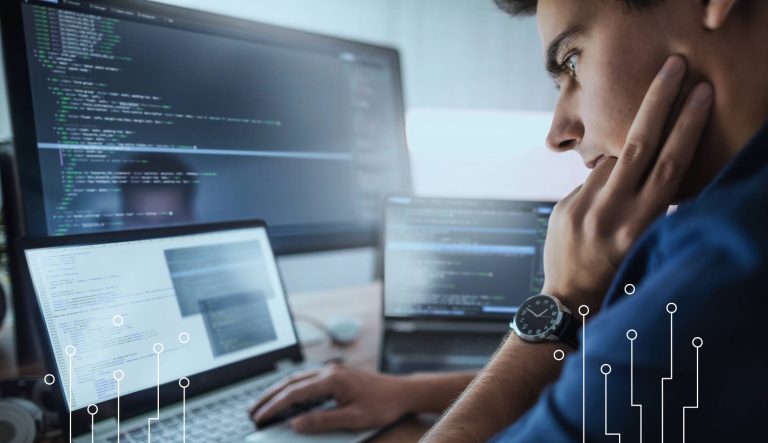 Programista analizujący kod źródłowy systemu IT na monitorze komputera. Opieka autorska oprogramowania, rozwój systemów informatycznych, aktualizacje, utrzymanie oraz wsparcie techniczne po wdrożeniu.