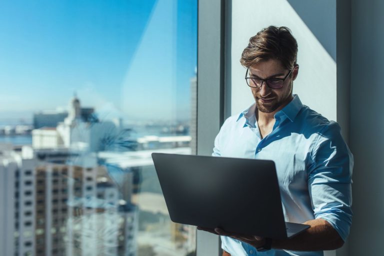 Specjalista pracujący na laptopie, symbolizujący monitoring sieci, bezpieczeństwo IT i zapewnienie ciągłości działania systemów informatycznych w firmie doradczej.